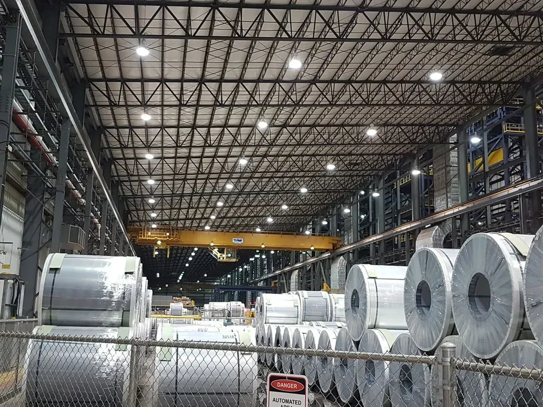 Overhead crane placing a steel coil in dense two high storage